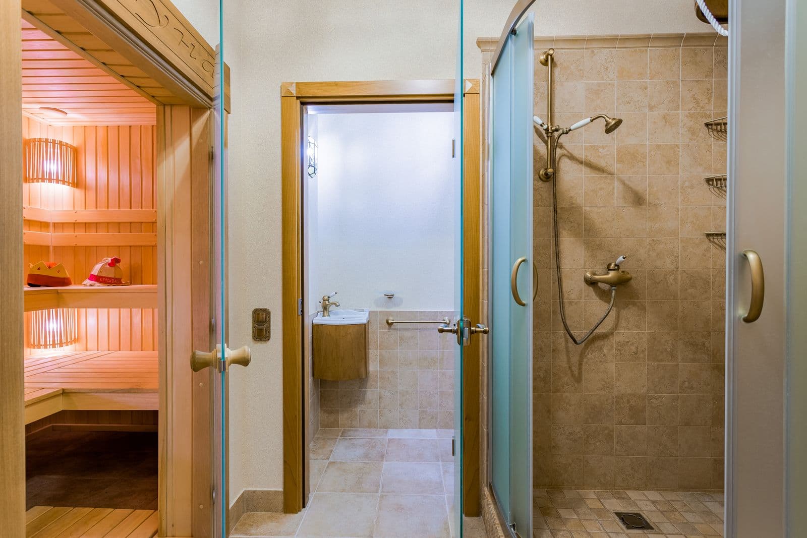 Sauna con puerta de vidrio junto a una regadera y un lavabo