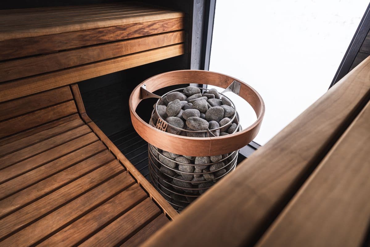 Interior de una sauna mediana con una estufa de piedras al centro